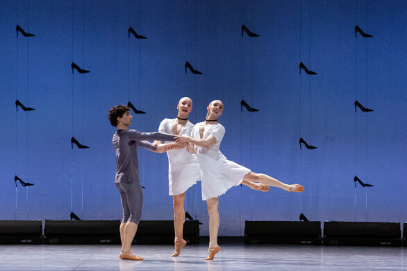 un ballerino vestito di grigio balla con due ballerini che eseguono un attitude