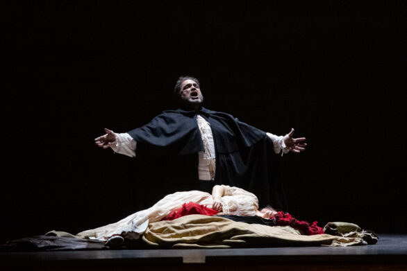 Prospettiva ingrandita del palco. Degli attori sono in scena durante l'opera "Rigoletto". Un uomo piange una donna distesa sul pavimento