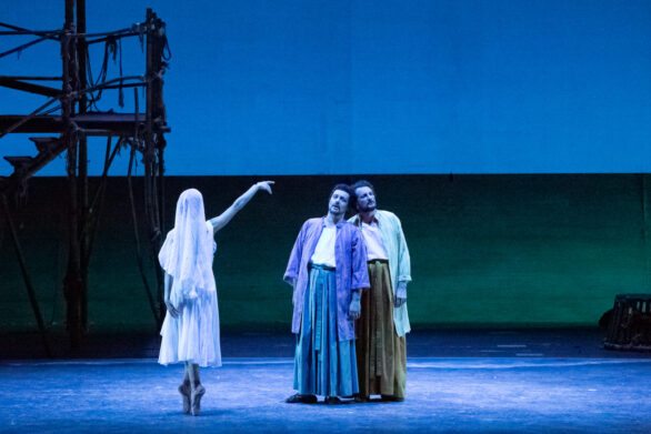 Due attori in maschera sono sul palco immersi nei loro personaggi durante l'opera "Les pêcheurs de perles". Accanto a loro c'è una donna coperta da un telo bianco