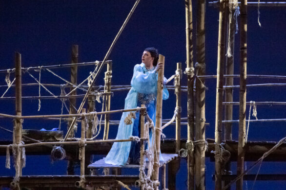 attrice in maschera sul palco immersa nel suo personaggio durante l'opera "Les pêcheurs de perles". Si trova sopra un impalcatura di legno