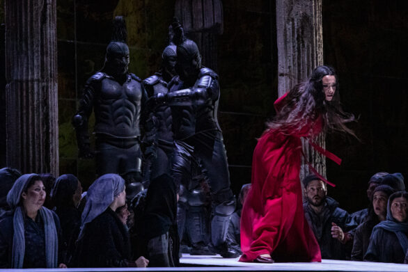 Scena dell'opera "Turandot". Una donna vestita di rosso sul palco è immersa nel suo personaggio. Altri attori sono presenti sul palco