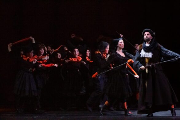 Attori in scena sul palco durante l'opera "Le allegre comari di Falstaff". Sono tutti vestiti di nero