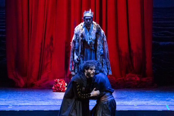 attori durante una scena drammatica. L'interprete del re osserva altri due uomini combattere. Durante il combattimento uno dei personaggi viene trafitto dalla spada dell'altro.